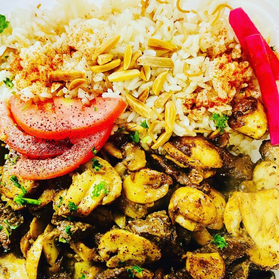 Middle-Eastern dish with rice, sliced tomatoes, pickled turnips, and seasoned meat with mushrooms.